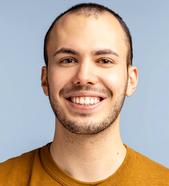 Smiling man in mustard shirt against blue background for dental practice portrait