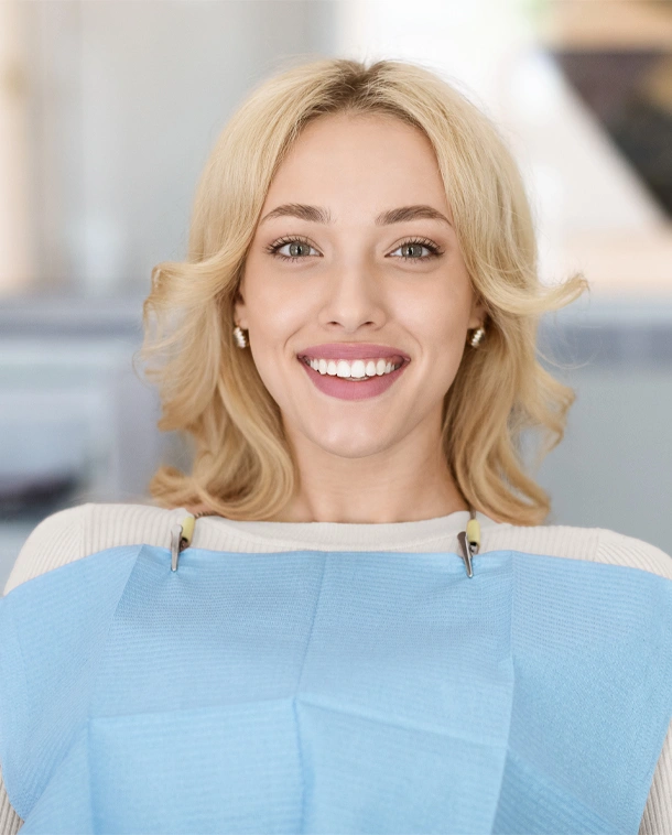 Smiling woman wearing dental bib in modern dental office setting.