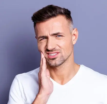 Man holding cheek in pain, suggesting dental discomfort or toothache symptoms.